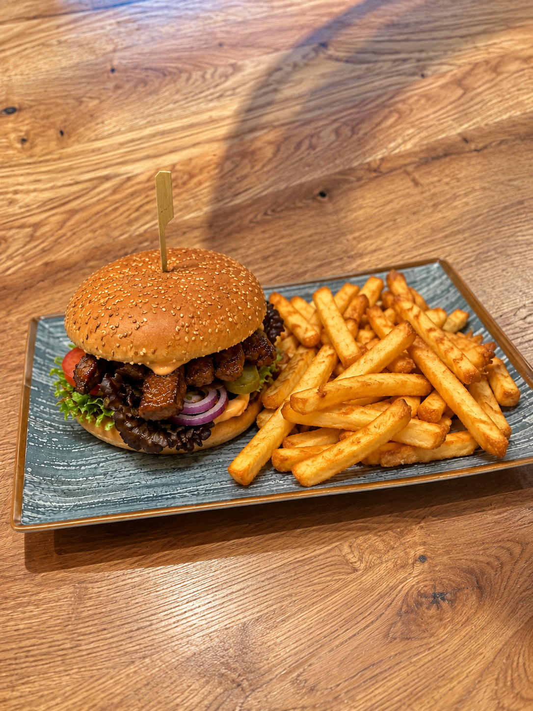 Rinderstreifen-Burger im Sesam-Bun mit Salat, Tomate und Gurke, dazu Pommes frites